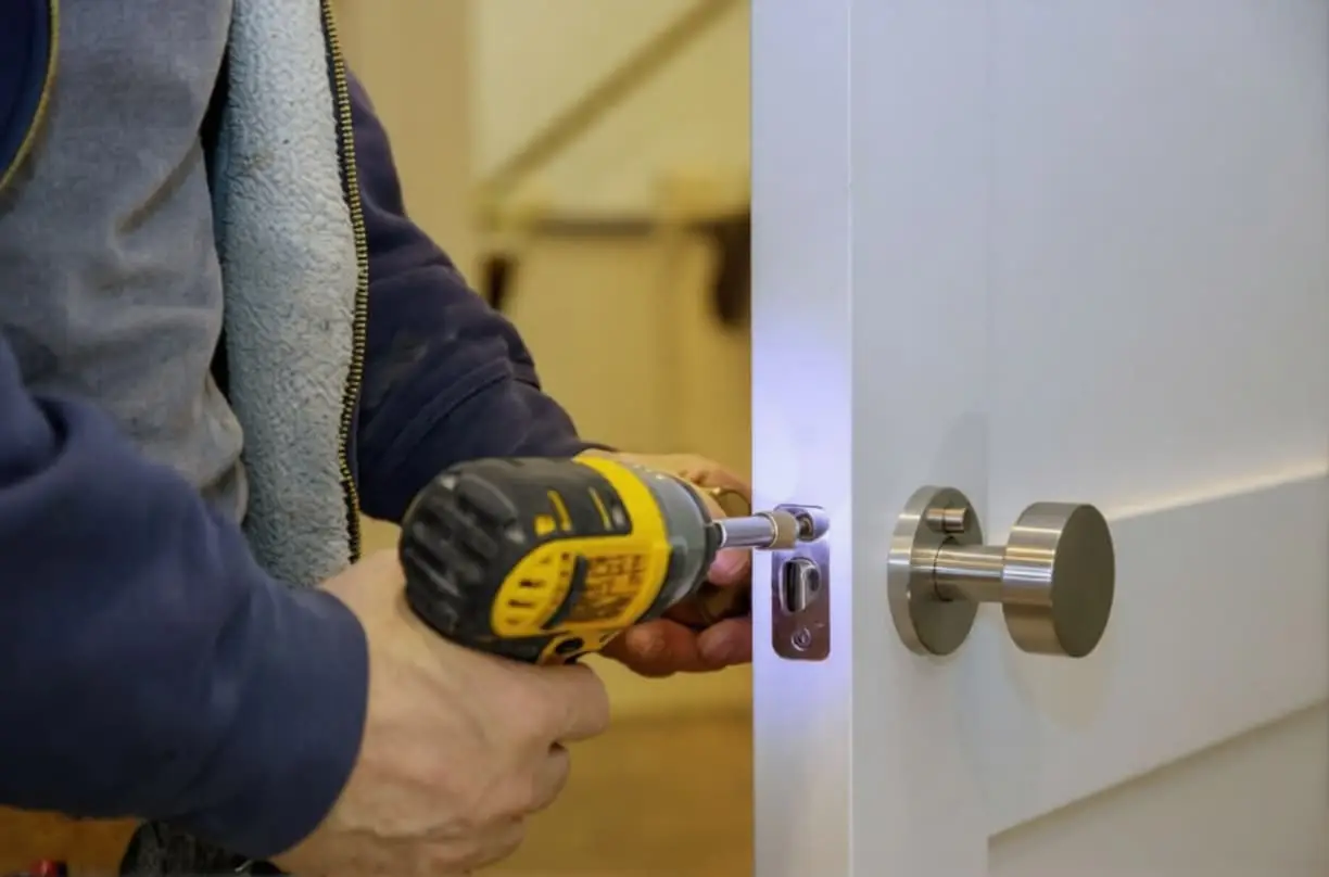 אדם פורץ דלת לבנה עם מברגה - מוביל לעמוד פריצת דלתות